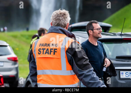 Seljalandsfoss, Islande - 14 juin 2018 : : parking lot par cascade aux gros plan du gardien de sécurité général écrit des billets à l'orange et les touristes vest w Banque D'Images