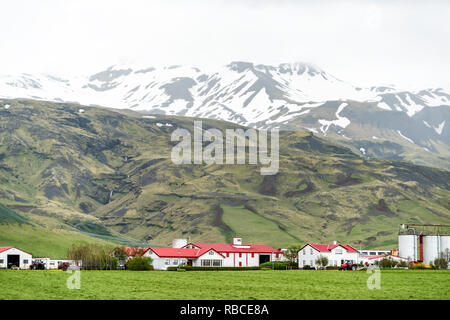 Vue d'un paysage de montagne vert par jour nuageux, southern ring road ou cercle d'or et de maisons de ferme près de Vik, village ville Banque D'Images