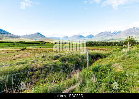 Vue sur la montagne près de Akureyri Sulur avec ciel bleu et de pâturage clôture de ferme avec de l'herbe verte au cours de journée ensoleillée Banque D'Images