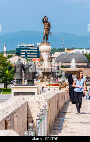 Skopje, Macédoine - 10 juin 2013 : fille qui marche sur le pont, faisant instrument de musique, célèbre sculptures comme Philip Deuxième de Macédoine ou Saints Banque D'Images