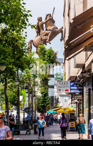 Skopje, Macédoine - Juin 10, 2013 Ville : vue sur la rue sur une immense statue en bronze d'Alexandre le Grand à la place de la Macédoine derrière les arbres. Personnes, tou Banque D'Images