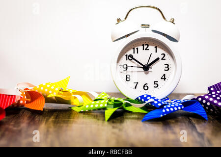 Arc-en-ciel coloré et virevents réveil blanc sur une planche en bois pour le plaisir de l'arrière-plan joyeux printemps, été, Fête, bébé, l'heure d'été Banque D'Images