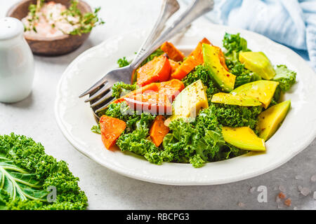 Salade de chou vert sain avec de l'avocat et de patates douces cuites au four. Régime alimentaire à base de plantes. L'alimentation, de désintoxication concept Vue de dessus, fond blanc. Banque D'Images