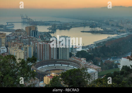 La ville espagnole de Malaga au coucher du soleil. Port et de la vieille ville avec un anneau de taureau ci-dessus. Les bâtiments et les navires dans le port peut être vu. dans le backgroun Banque D'Images