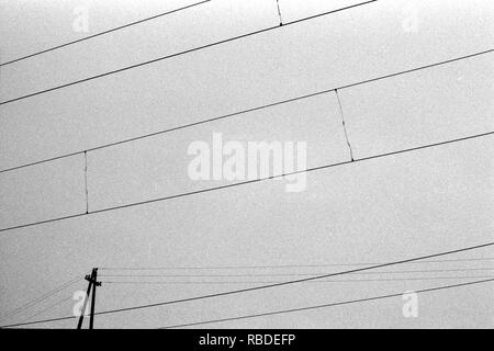 Résumé des lignes de câble électrique avec sky film granuleux sur la texture. La photographie de rue minime. Film en noir et blanc. Moody sky film historique Banque D'Images