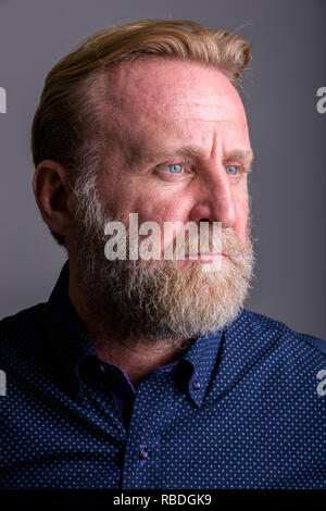 Visage d'homme barbu d'âge mûr pense en arrière-plan gris Banque D'Images