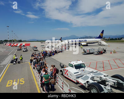 Quelques passagers sur le tarmac de l'aéroport de Milan Bergamo. Voyageurs avec des bagages à l'aire de Orio al Serio prêt à bord d'un avion de Ryanair Banque D'Images