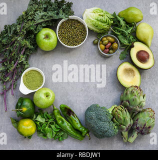 La sélection d'aliments verts en bonne santé pour les végétariens : avocat, pommes de terre, le brocoli, les artichauts, les mandarines, les haricots mungo, de laitue, d'olives, roquette, chou vert, thé matcha, poires, sur fond noir en gris Banque D'Images