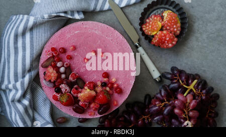 Raw Vegan cake aux fruits rouges, crème de noix de cajou, noix de beurre et le lait de coco, et la base fait d'amandes, dates et abricots séchés, flocons d'avoine, soit lyophilisé berry, vue de dessus, l'arrière-plan gris pierre Banque D'Images