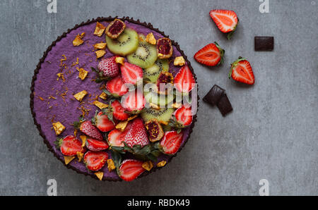 Raw Vegan gâteau avec fraise et kiwi, crème de noix de cajou, noix de beurre et le lait de coco, et la base fait d'amandes, dates et abricots séchés, flocons d'avoine, soit lyophilisé berry, vue du dessus Banque D'Images