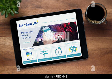 Le site web de la Standard Life est vu sur une tablette iPad, sur une table en bois avec une machine à expresso et d'une plante (usage éditorial uniquement). Banque D'Images