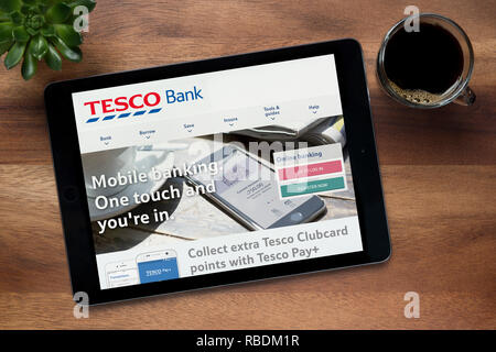 Le site web de banque Tesco est vu sur un iPad tablet, sur une table en bois avec une machine à expresso et d'une plante (usage éditorial uniquement). Banque D'Images