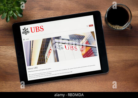 Le site internet de la banque UBS est vu sur un iPad tablet, sur une table en bois avec une machine à expresso et d'une plante (usage éditorial uniquement). Banque D'Images