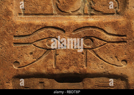 Close up fond de mur de pierre antique sculpté avec bas-relief de l'Égypte ancienne, de l'Œil ouadjet de Ra ou Horus, front view Banque D'Images