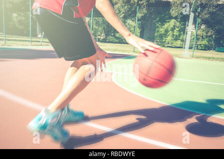 Adolescent jouer au basket-ball en plein air - sportive saine vie adolescents concept au printemps ou l'heure d'été Banque D'Images