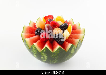 Fancy cut pastèque sur fond blanc avec l'intérieur de fruits assortis comme les petits fruits, raisins, ananas, oranges Banque D'Images