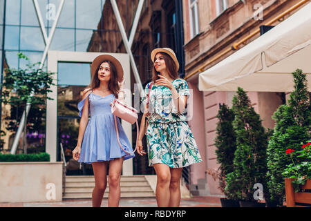 Portrait plein air de deux jeunes belles femmes walking on city street. Meilleurs amis, s'amuser et pointant vers le haut Banque D'Images