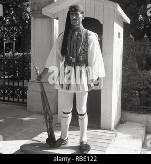 Années 1950, historique, la protection (Grec Evzone) en grande tenue uniforme avec son fusil sur le pas de guérite, Athènes, Grèce. La Garde présidentielle est une cérémonie d'infanterie qui garde la tombe du Soldat inconnu et le manoir présidentiel à Athènes. Banque D'Images