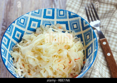 Salade de chou mariné. Apéritif traditionnel russe de la choucroute avec des carottes dans une assiette sur une table en bois blanc. Style rustique. Focus sélectif et copie espace, close-up. Banque D'Images