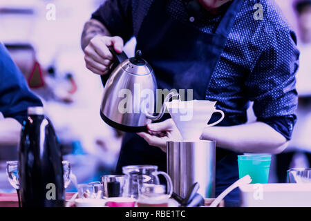 Verser barista professionnel de l'eau bouillante dans le filtre électrique spécial, la préparation de café filtre. Fond de couleur pourpre Banque D'Images