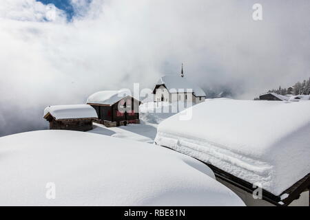 Refuges de montagne couverte de neige et église entourée de nuages Bettmeralp Française, canton du Valais Suisse Europe Banque D'Images