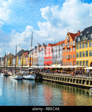 Les gens qui marchent au remblai Nyhavn ensoleillée avec des bateaux amarrés, Copenhague, Danemark Banque D'Images