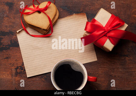 Valentine's day Greeting card with gift box, tasse de café et biscuits en forme de coeur sur fond de bois. Vue de dessus avec le bloc-notes pour vos messages d'accueil. Télévision Banque D'Images