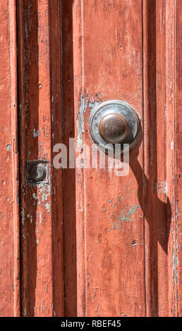 Photographie d'une rouge, weathered wood porte d'un petit village en Toscane. Poignée en laiton est usé et serrure est recouvert d'une araignée. Banque D'Images