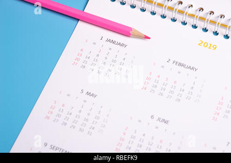 Crayon rouge et calendrier sur fond bleu Banque D'Images