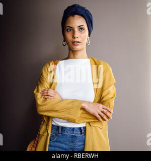 Portrait d'un jeune, élégante et belle femme du Moyen-Orient dans un turban hijab foulard et élégant sur le thème pastel les vêtements. Banque D'Images