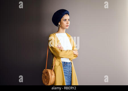 Portrait d'un jeune, élégante et belle femme du Moyen-Orient dans un turban hijab foulard et élégant sur le thème pastel les vêtements. Banque D'Images