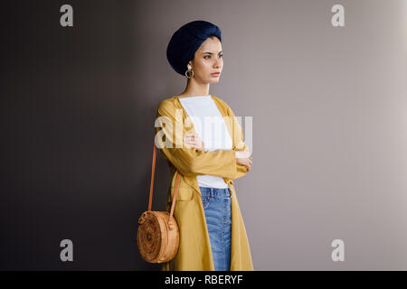 Portrait d'un jeune, élégante et belle femme du Moyen-Orient dans un turban hijab foulard et élégant sur le thème pastel les vêtements. Banque D'Images