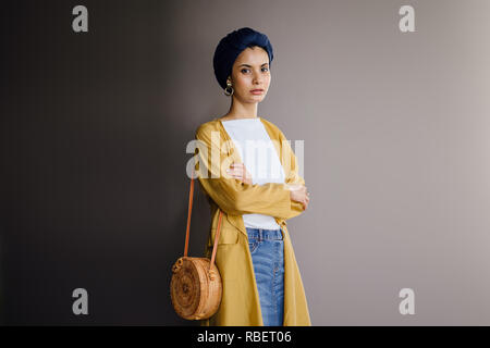 Portrait d'un jeune, élégante et belle femme du Moyen-Orient dans un turban hijab foulard et élégant sur le thème pastel les vêtements. Banque D'Images