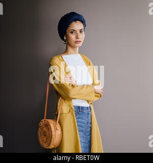 Portrait d'un jeune, élégante et belle femme du Moyen-Orient dans un turban hijab foulard et élégant sur le thème pastel les vêtements. Banque D'Images