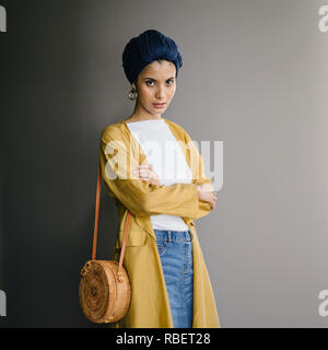 Portrait d'un jeune, élégante et belle femme du Moyen-Orient dans un turban hijab foulard et élégant sur le thème pastel les vêtements. Banque D'Images