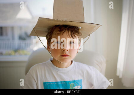 Portrait d'un jeune garçon portant un chapeau en carton. Banque D'Images