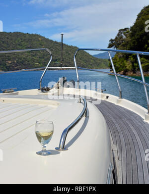 Un verre de vin de Sauvignon Blanc sur le pont d'un bateau à moteur de luxe dans le Marlborough Sounds en Nouvelle-Zélande. Banque D'Images