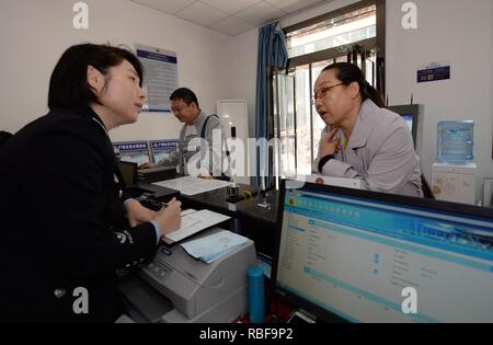 (190110) -- BEIJING, 10 janvier 2019 (Xinhua) -- une policière Li Guoyan (L) s'occupe de l'enregistrement des ménages pour une femme Gaoxinlu au poste de police à Xi'an, capitale de la Province chinoise de Shaanxi nord-ouest, le 29 mars 2018. En novembre 2013, le 18e Comité central du Parti communiste de Chine a tenu sa troisième session plénière de se concentrer sur l'approfondissement de manière globale la réforme. La Chine a réalisé des progrès dans l'approfondissement de la réforme dans l'appareil judiciaire et des systèmes sociaux dans les cinq ans après la session. (Xinhua/Li Yibo) Banque D'Images