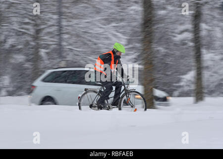 Munich Riem, Deutschland. 10 janvier, 2019. Le chaos de la neige sur les rues de Bavière - probablement celui qui vient en vélo sur son lieu de travail, comme ce cycliste avec gilet de signal de la conduite sur la neige, neige-couvertes - piste cyclable à côté de lui.conduit une voiture : PKW neige continue sur 10.01.2019, s'assurer que le chaos, le chaos de la circulation de la neige, l'hiver en Bavière. Utilisation dans le monde entier | Credit : dpa/Alamy Live News/Alamy Live News Banque D'Images