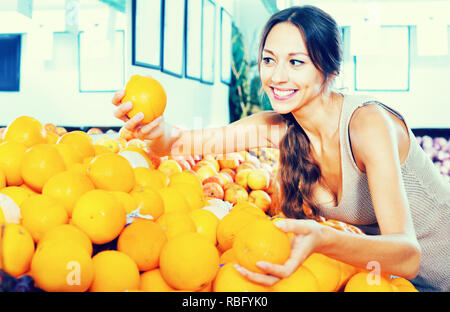 Jeune femme positive l'achat des oranges sur la place de marché Banque D'Images