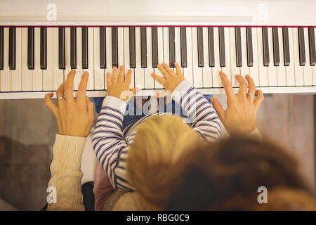 Tout-petit enfant et positive douce mère joue du piano. Au début de l'éducation musicale pour les petits enfants, les enfants à l'apprentissage des instruments de musique d'accueil Banque D'Images