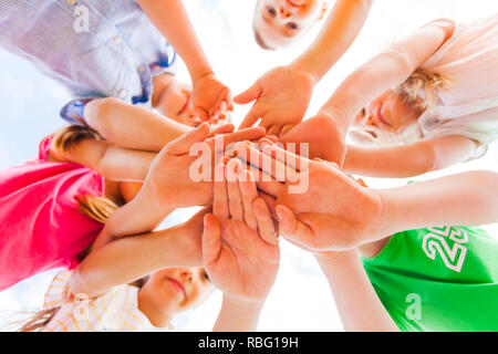 Enfants mains tenant fermement ensemble en cercle portant l'un sur l'autre sur un fond blanc, vue du bas. Concept d'équipe Banque D'Images