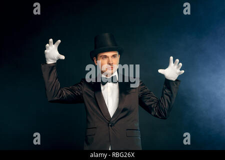 Le port de gants combinaison professionnelle showman et top hat standing isolé sur fond bleu et noir des gestes atmosphère mystérieuse Banque D'Images