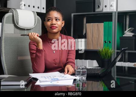 Portrait de jeune femme noire Utilisation des graphiques et diagrammes at Desk in office Banque D'Images