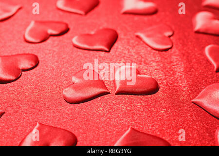 De nombreux coeurs rouges sur fond rouge. L'amour romantique, Saint Valentin, anniversaire, mariage, vacances. Focus sélectif. Banque D'Images