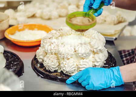 Les mains gantées dans processus de fabrication de desserts et gâteaux à la meringue. Concept de production de confiseries Banque D'Images