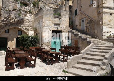 Matera, Italie. Vieille ville restaurant tables en bois en plein air. Banque D'Images