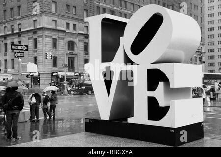 NEW YORK, USA - 7 juin 2013 : Les gens passent devant l'amour de la sculpture dans la pluie dans la ville de New York. Le célèbre monument de Robert Indiana est situé sur la 6e Avenue Banque D'Images