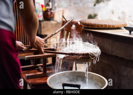 Femme préparant les nouilles de riz traditionnellement à la maison sur une machine vintage Banque D'Images