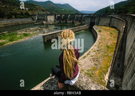 Femme assise près d'une centrale hydroélectrique. Banque D'Images